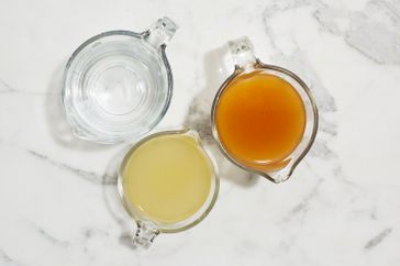 measuring cups of chicken vegetable broth and water