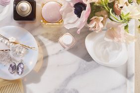 delicate jewelry, perfume, and flowers on marble tray