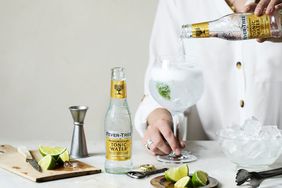 tonic water being poured into glass filled with ice