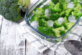 Blanched broccoli cabbage cooling down in cold water in a glass dish on white table