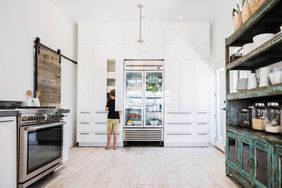 Boy looking in cupboard in kitchen next to refrigerator