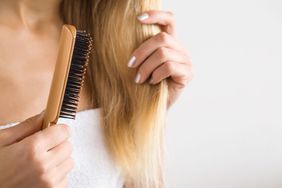 Woman's hand brushing blonde hair. Cares about a healthy and clean hair.