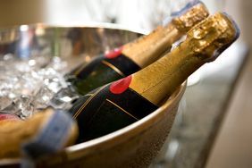 champagne bottles resting in a metal bowl on ice