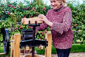 Martha Sewart pressing apples into a barrel for apple cider