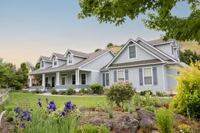 Suburban home exterior at sunset with lawn and garden visible