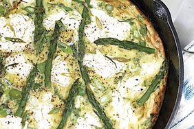 overhead view of a frittata with asparagus, goat cheese, and herbs