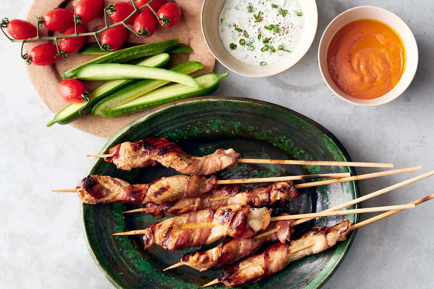 Chicken on kebabs with dipping sauces and vegetables