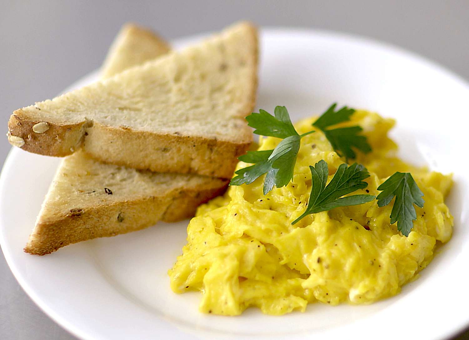 scrambled eggs and toast on a white plate