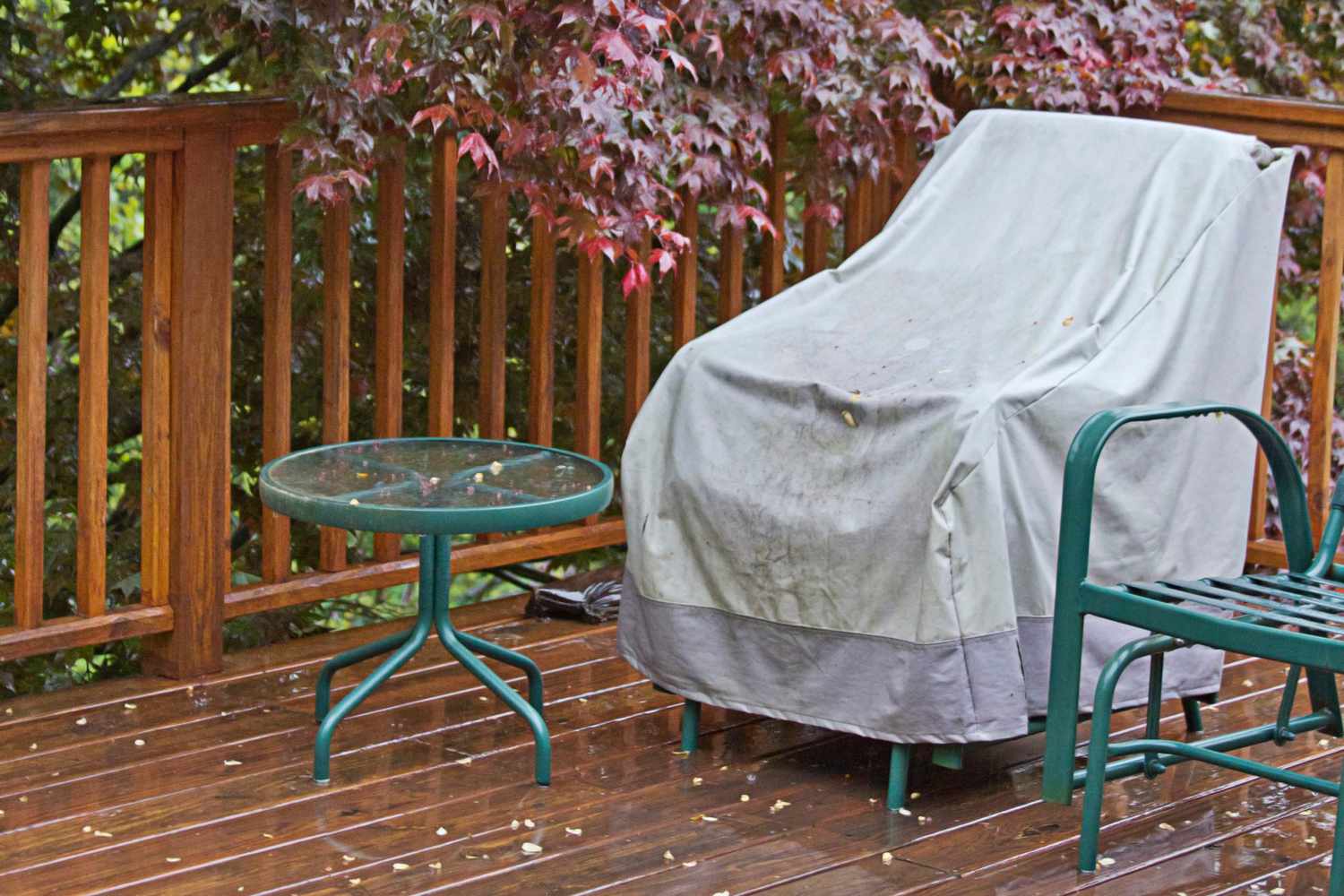 A rain wet wooden deck with a covered lawn chair