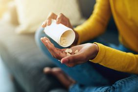 woman pouring vitamin supplements into hand