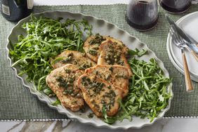 Pork scaloppine on white dish with arugula