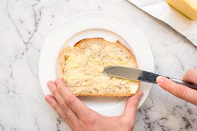 person buttering a slice of bread