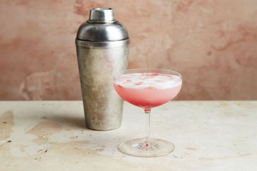 Pink cocktail next to cocktail shaker