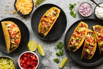 Tacos with toppings around them in bowls