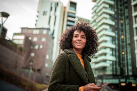 woman with curly hair smiling outside